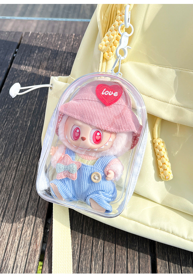 A transparent PVC display bag attached to a yellow backpack. The bag features a Labubu figure with a pink hat and pastel overalls, showcasing a playful and functional way to carry collectibles.