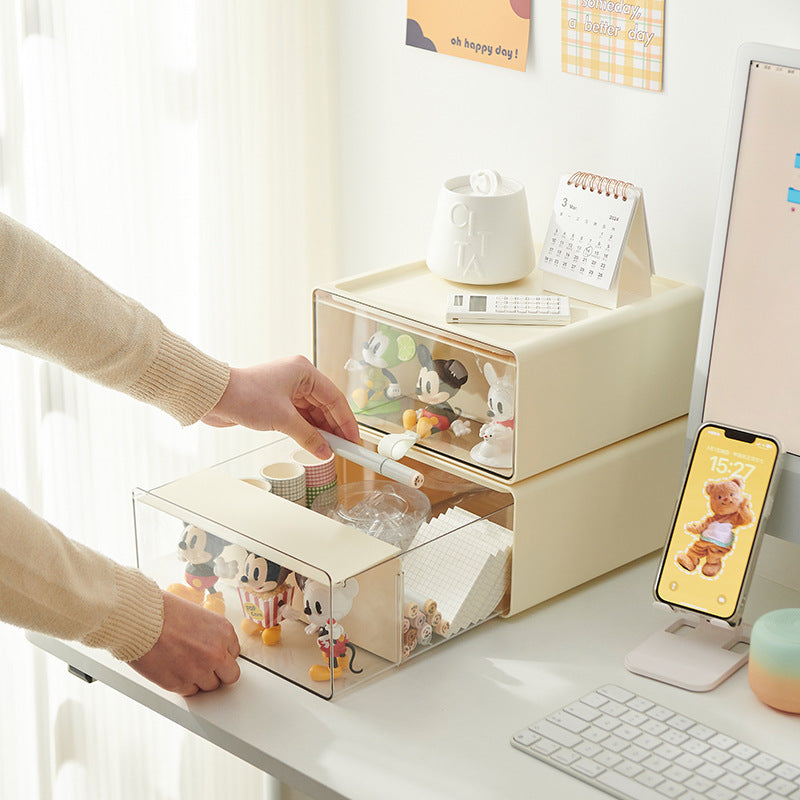 Person pulling out a clear drawer-style storage box filled with mini figures and accessories on a tidy desk setup
