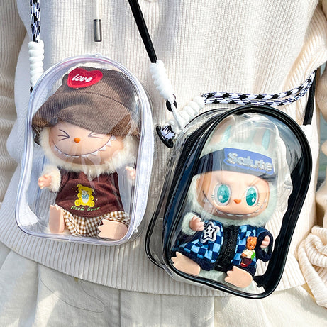 Two transparent PVC display bags featuring collectible Labubu figures. One bag has a white strap and a Labubu figure in a brown sweater, and the other has a black strap and a Labubu figure in a blue checkerboard jacket. Perfect for displaying and protecting Pop Mart collectibles.