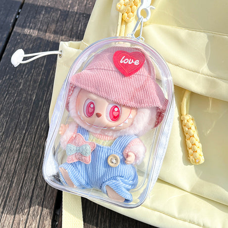 A transparent PVC display bag attached to a yellow backpack. The bag features a Labubu figure with a pink hat and pastel overalls, showcasing a playful and functional way to carry collectibles.