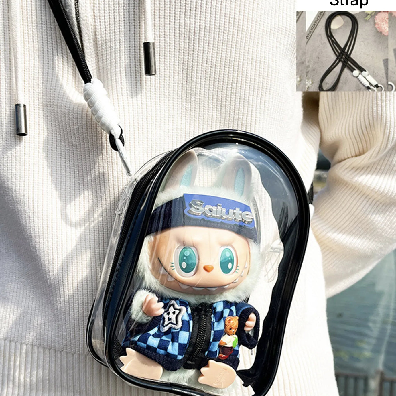 A transparent PVC display bag with a black strap, showcasing a Labubu figure in a blue checkerboard jacket. The bag is ideal for displaying Pop Mart figures while keeping them protected.