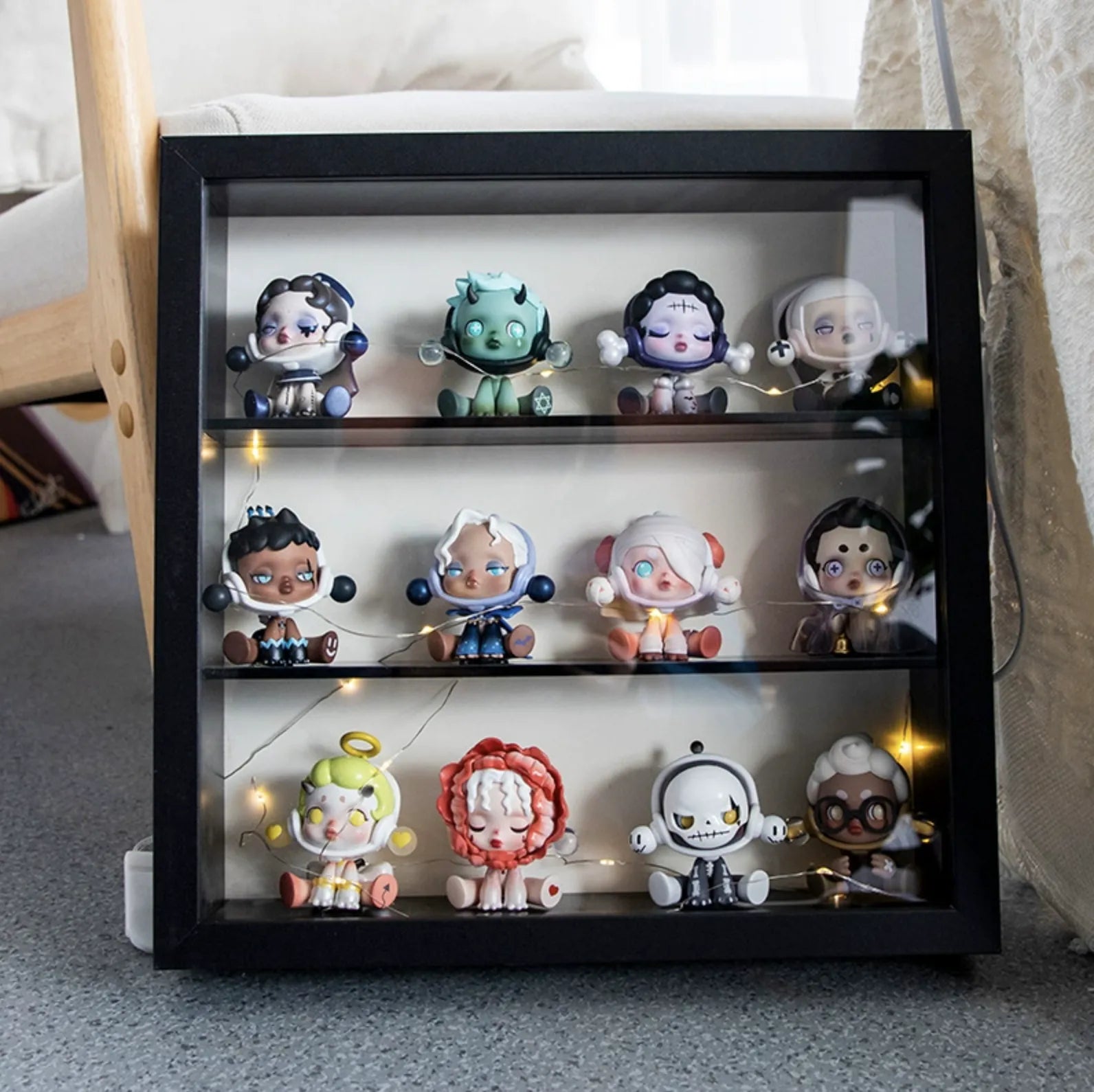 A squared black wooden display case from Fig Palace with three layers, featuring a collection of designed Skullpanda figures from Popmart, each with distinct colors and styles,neatly arranged for display.