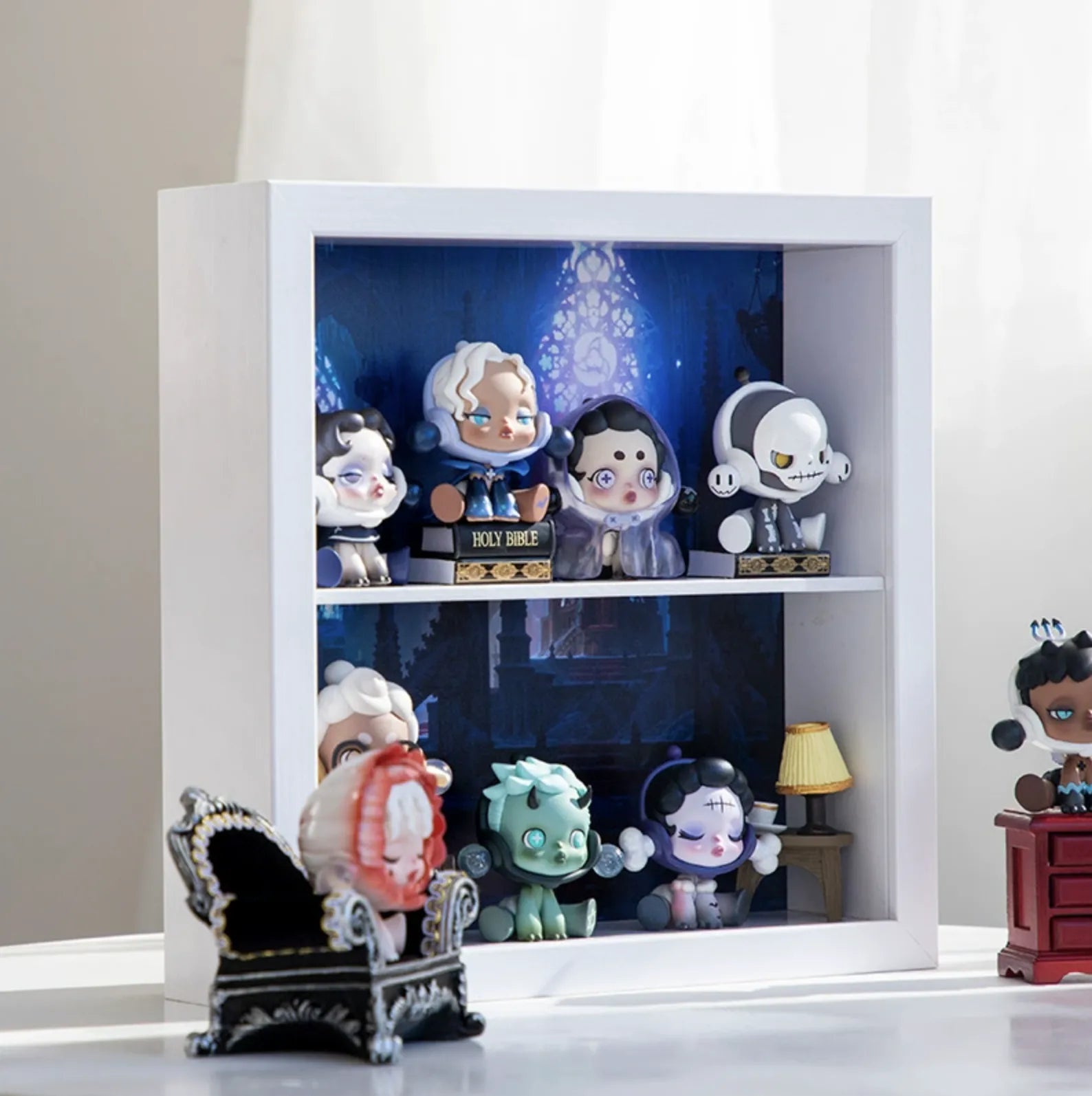 A squared white wooden display case from Fig Palace with two layers,featuring a collection of designed Skullpanda figures from Popmart, each with distinct colors and styles,neatly arranged for display.