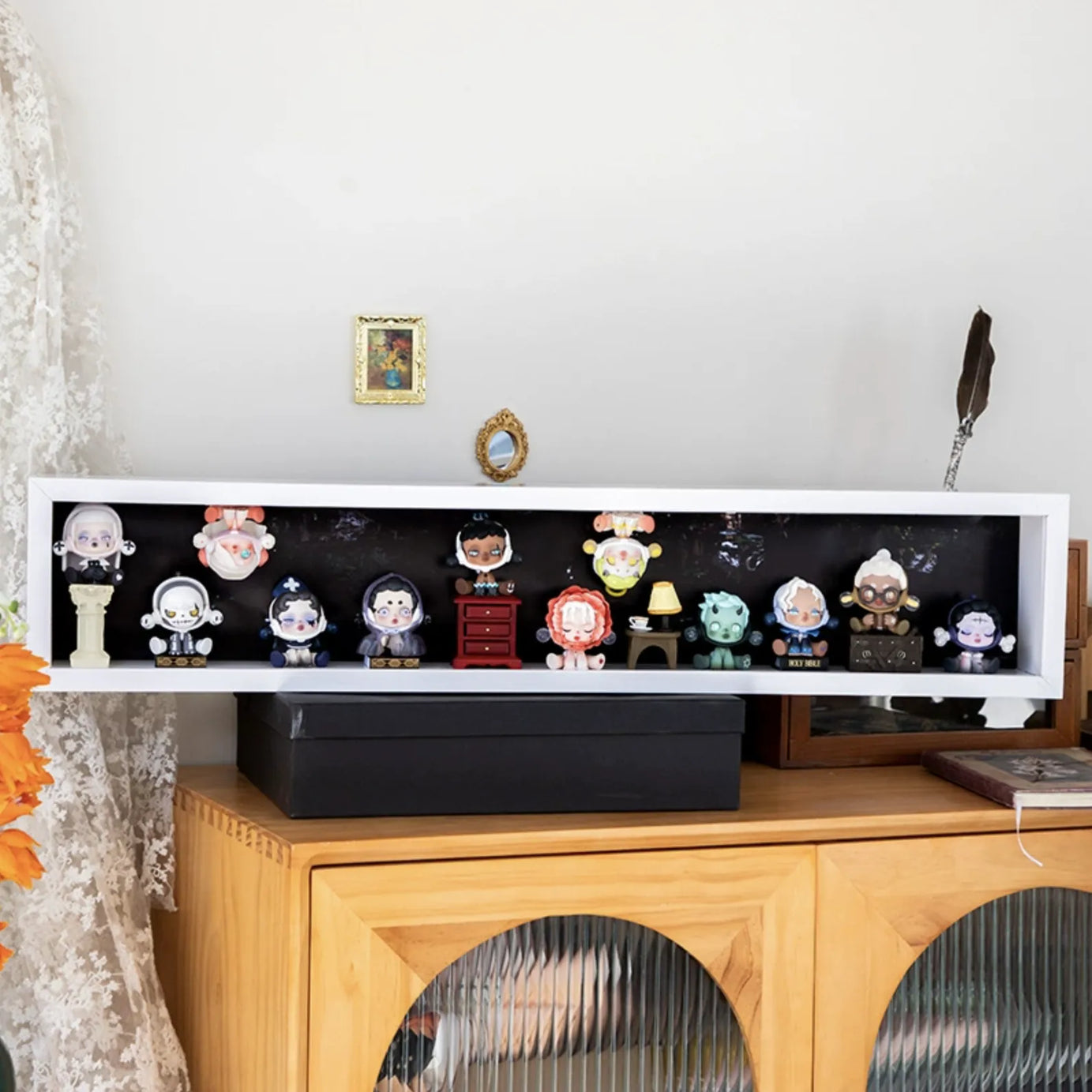 A 80cm-wide white wooden display case from Fig Palace with one layer,featuring a collection of designed Skullpanda figures from Popmart, each with distinct colors and styles,neatly arranged for display.